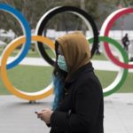 woman-wearing-a-face-mask-walks-past-the-olympic-rings-in-news-photo-1582746515