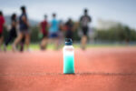 Close up Energy drink bottle on the Running track with blurred athlete  background