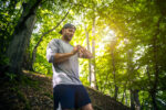 Trail runner with smart watch in green forest