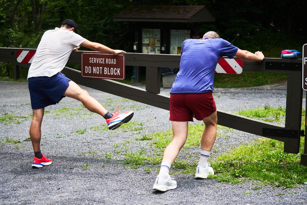 two men stretching at a trailhead